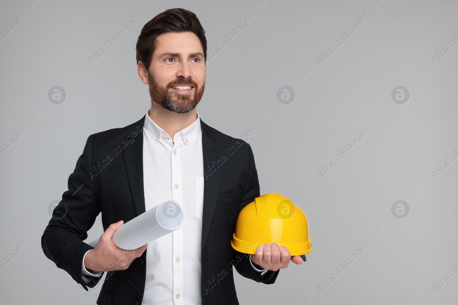 Photo of Architect with draft and hard hat on gray background, space for text