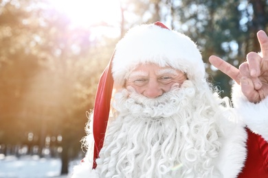 Photo of Happy Authentic Santa Claus showing rock gesture outdoors, space for text
