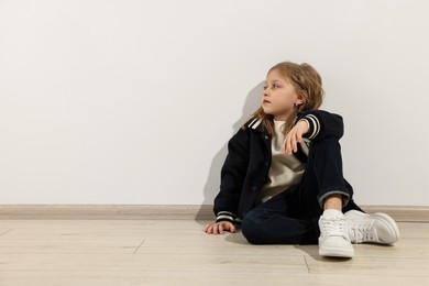 Photo of Fashion concept. Stylish girl sitting near white wall. Space for text
