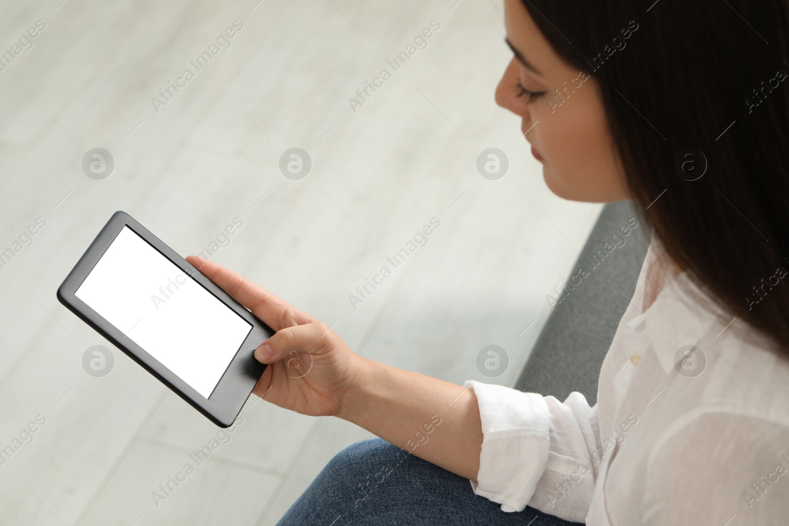 Photo of Young woman using e-book reader indoors, closeup