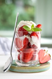 Photo of Delicious strawberries with whipped cream served on white wooden table indoors