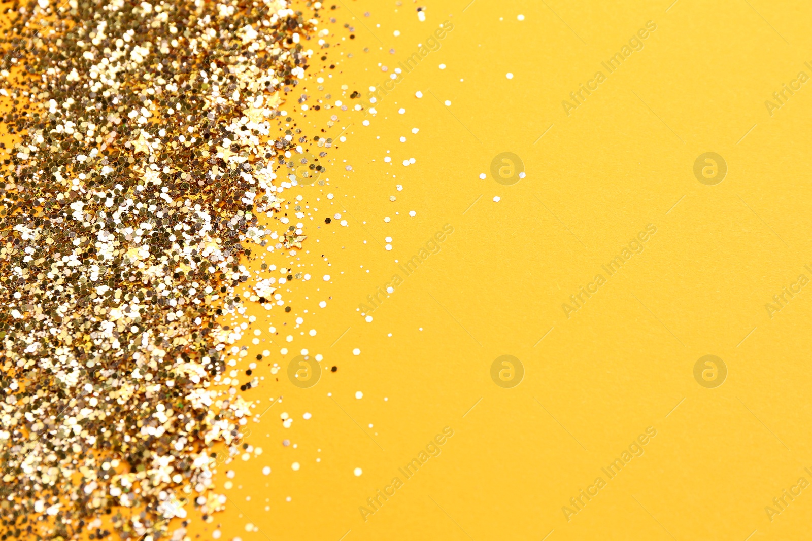 Photo of Shiny bright golden glitter on pale orange background. Space for text