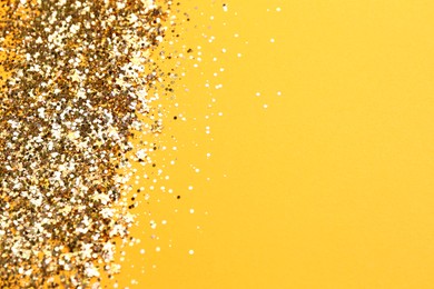 Photo of Shiny bright golden glitter on pale orange background. Space for text