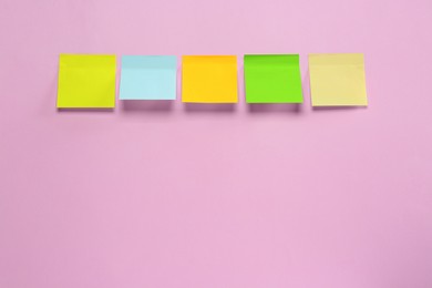 Photo of Blank colorful sticky notes on pink background, flat lay. Space for text