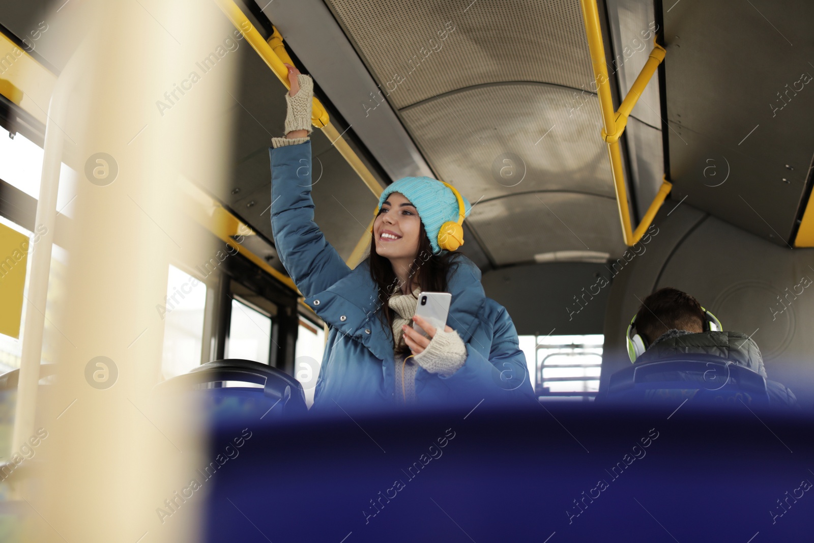 Photo of Young woman listening to music with headphones in public transport