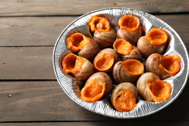 Delicious cooked snails on wooden table, closeup