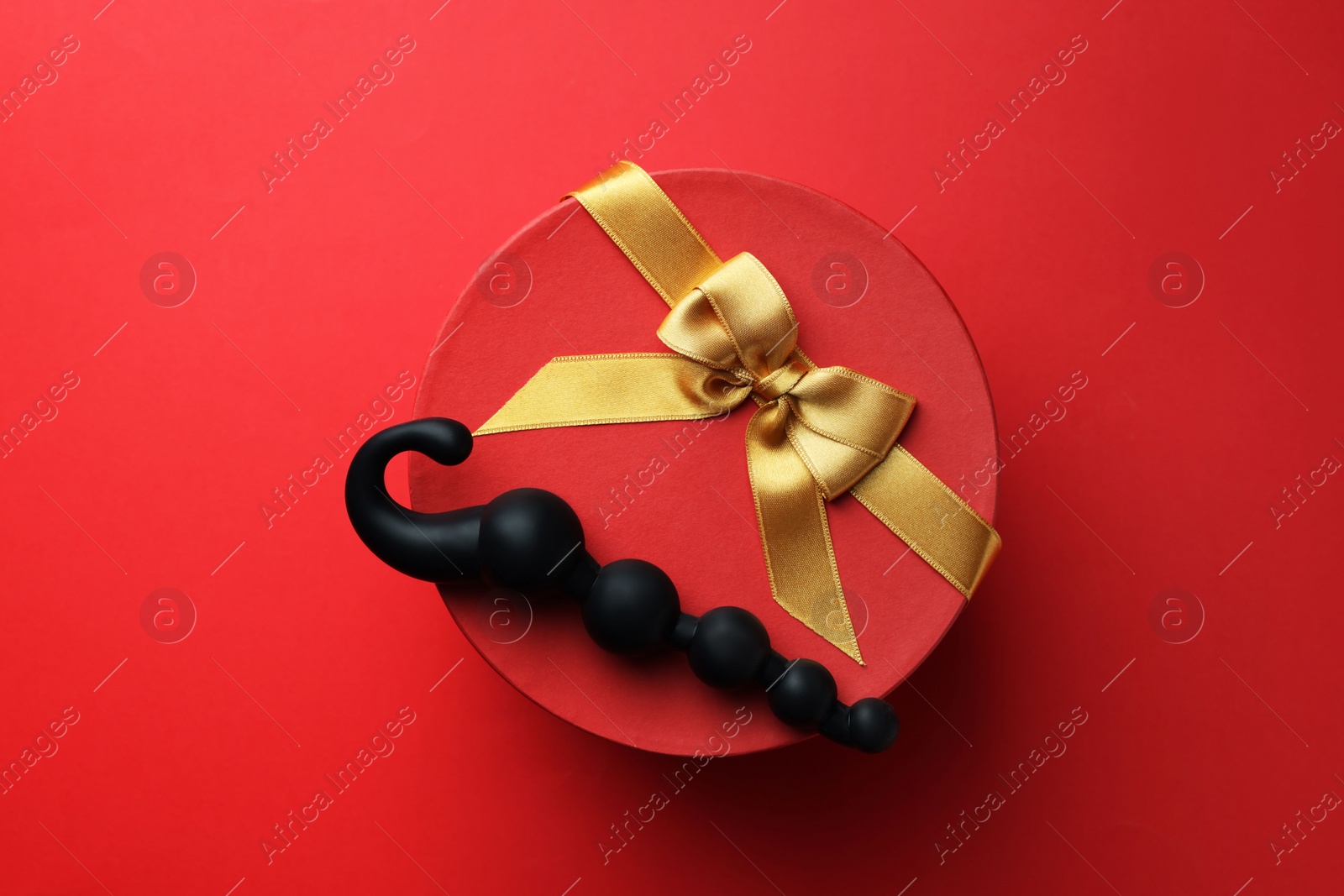 Photo of Gift box with sex toy on red background, top view