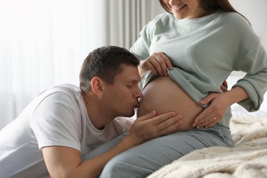 Photo of Young pregnant woman with her husband in bedroom, closeup
