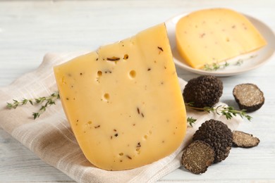 Photo of Delicious cheese, thyme and fresh black truffles on white wooden table, closeup