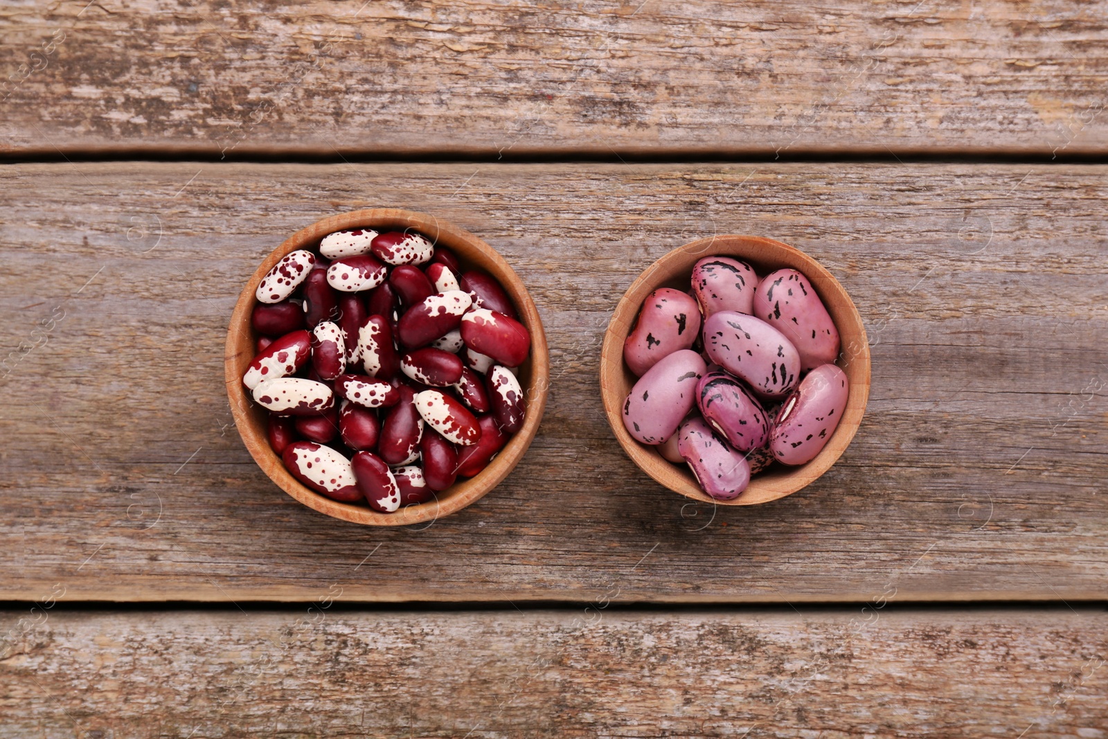 Photo of Different kinds of dry kidney beans on wooden table, flat lay