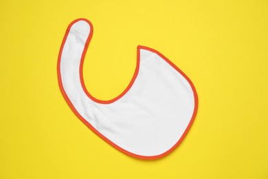 Photo of New baby bib on yellow background, top view. First food