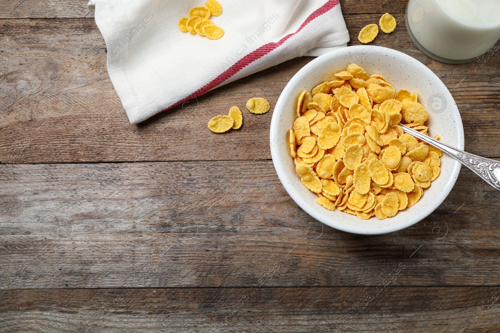 Photo of Tasty crispy corn flakes on wooden table, flat lay. Space for text