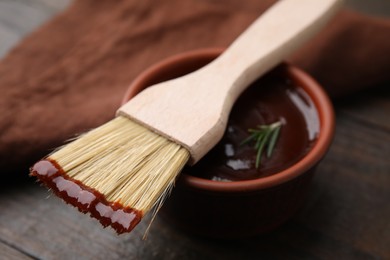 Marinade in bowl and basting brush on table, closeup