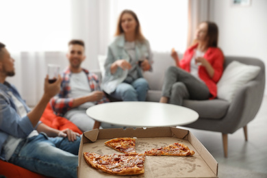 Photo of Group of friends having party at home, focus on pizza