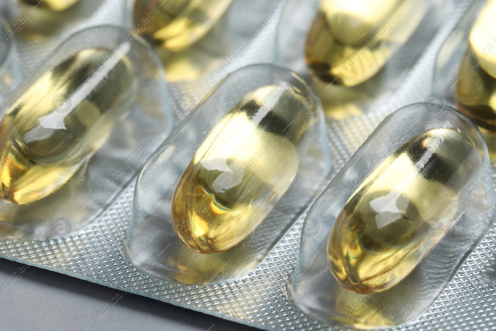 Photo of Yellow pills in blisters on grey background, closeup