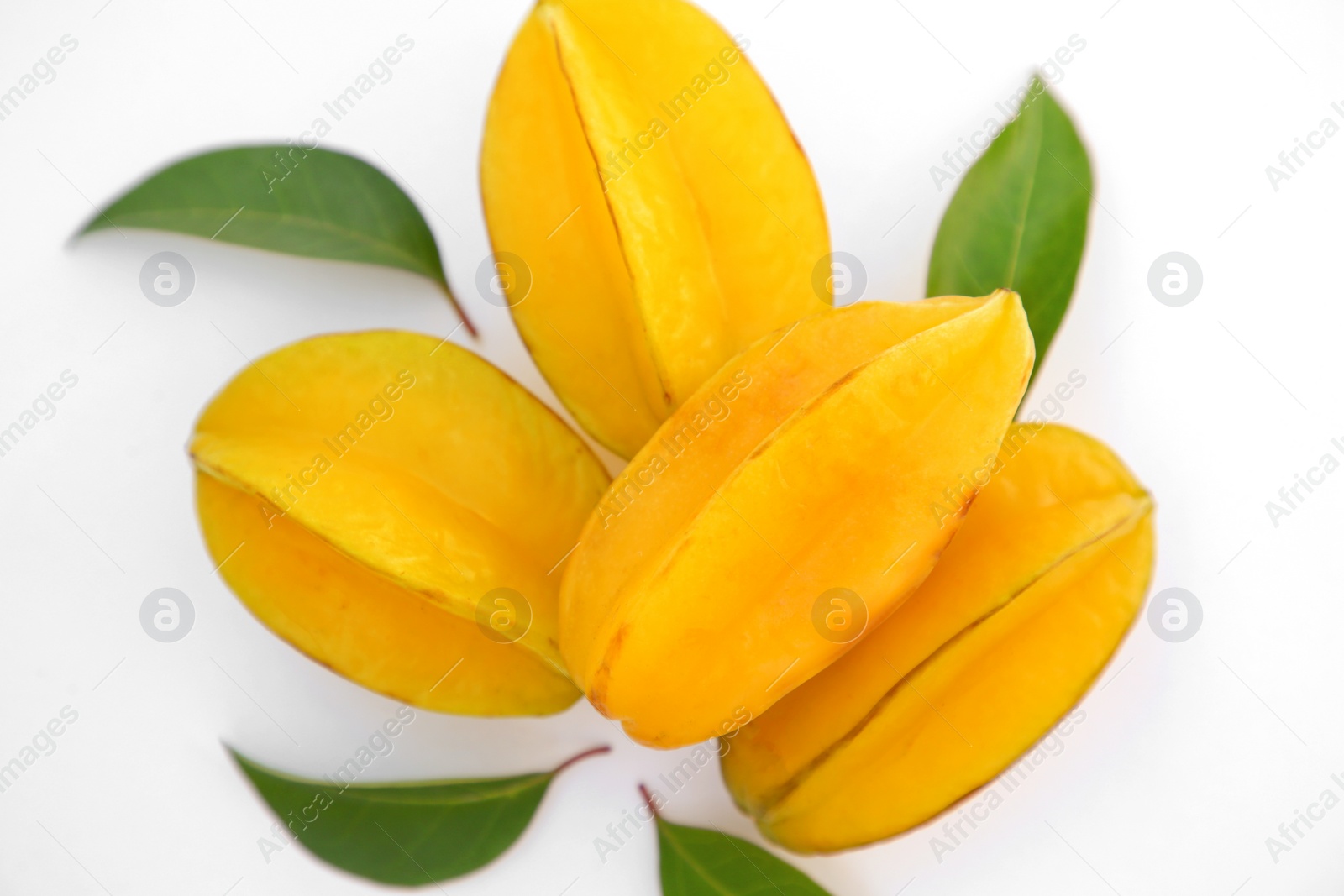 Photo of Delicious ripe carambolas with green leaves on white background, top view