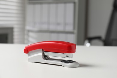 Photo of One stapler on white table indoors. Office stationery