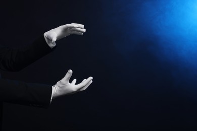 Photo of Magician holding something on dark background, closeup. Space for text