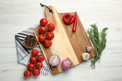 Photo of Cutting board and vegetables on white wooden table, flat lay. Cooking utensil