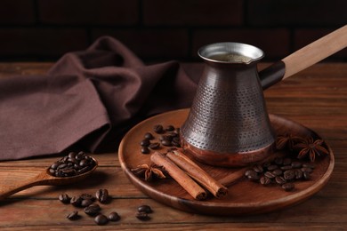 Photo of Cezve with Turkish coffee, beans and spices on wooden table, space for text