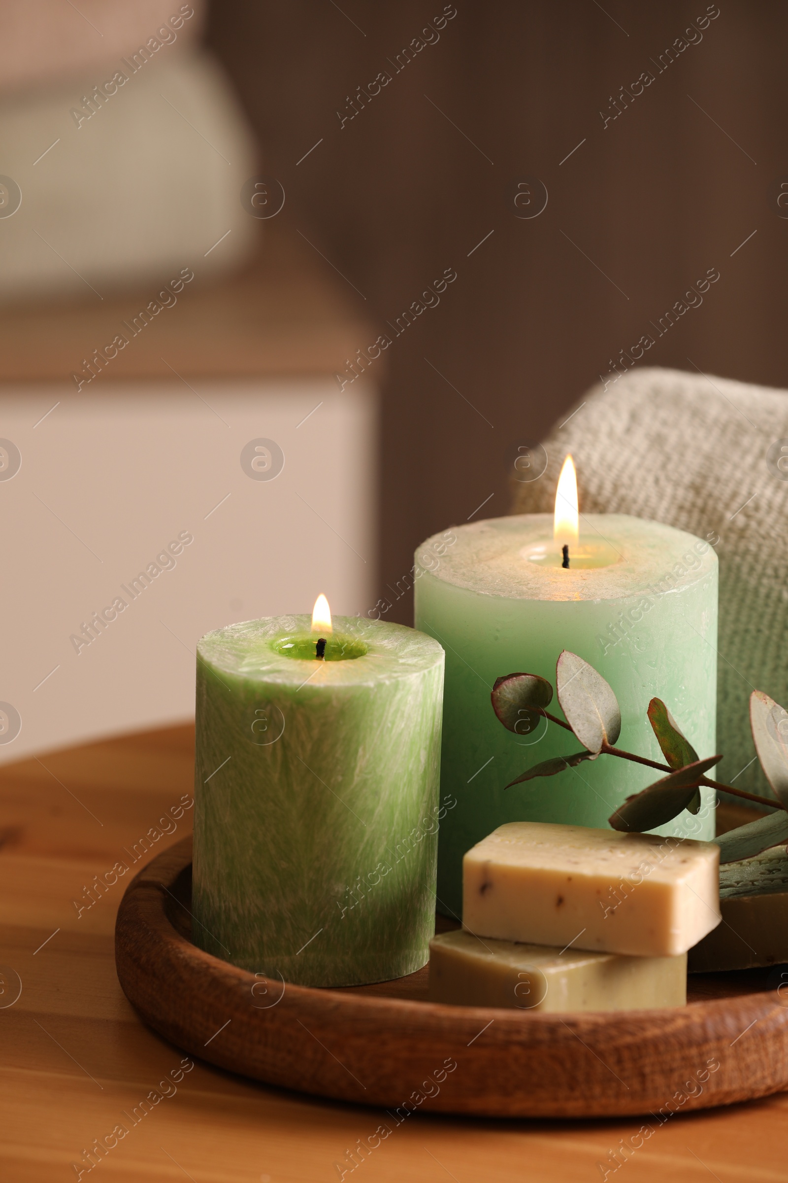 Photo of Spa composition. Burning candles, soap and eucalyptus branch on wooden table