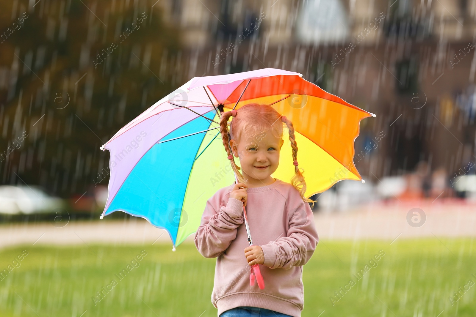 Photo of Cute little girl with bright umbrella in park