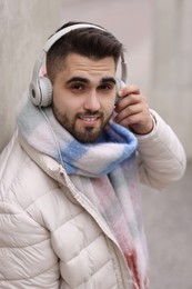 Smiling man in warm scarf and headphones on blurred background