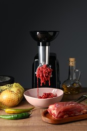 Electric meat grinder with minced beef and products on wooden table