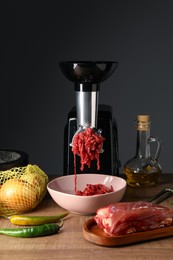 Photo of Electric meat grinder with minced beef and products on wooden table