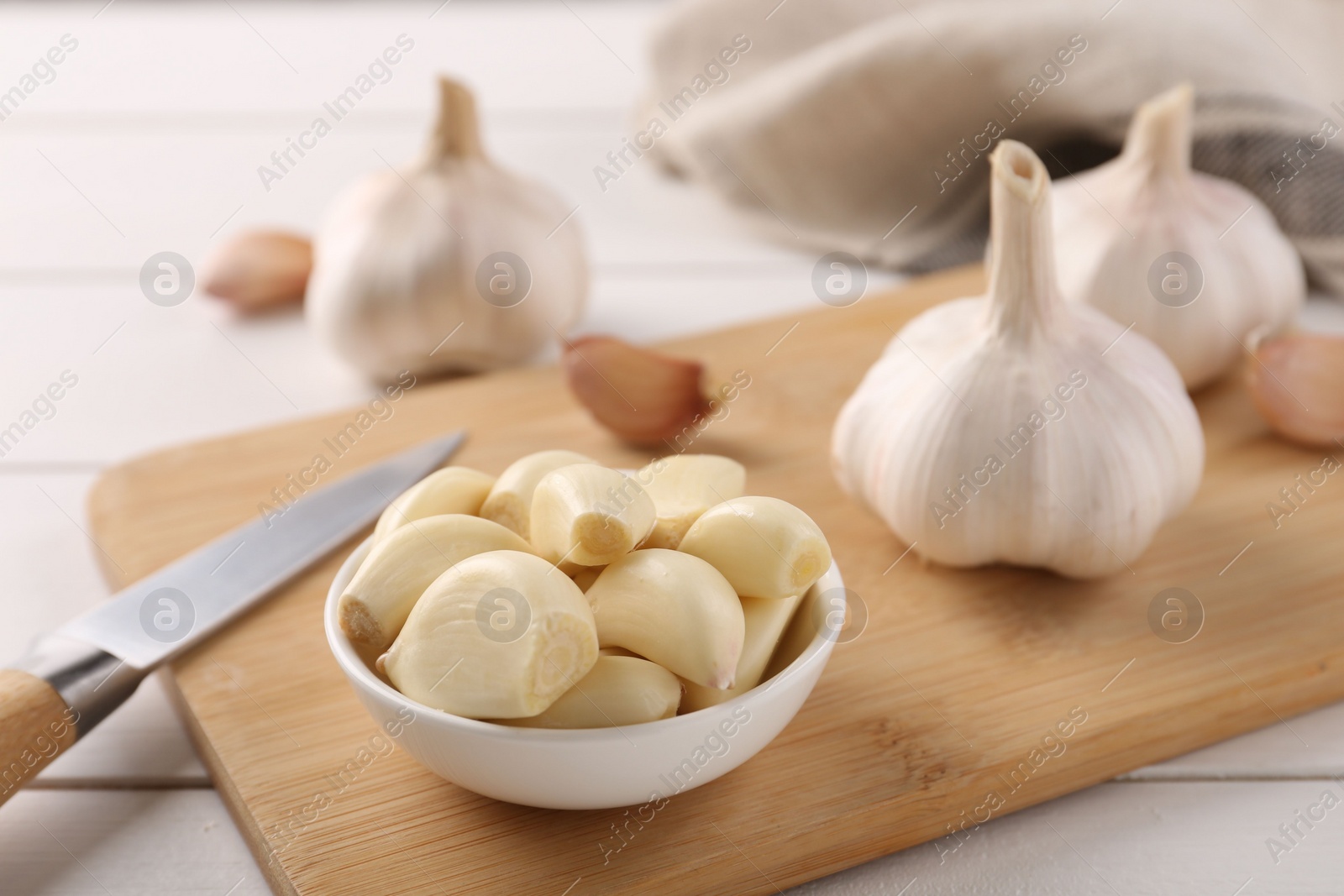 Photo of Fresh garlic and knife on white wooden table, closeup