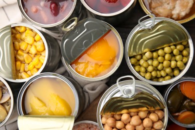 Open tin cans with different products on table, flat lay