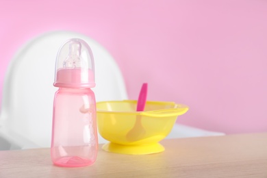 Photo of Set of plastic dishware on wooden table. Serving baby food