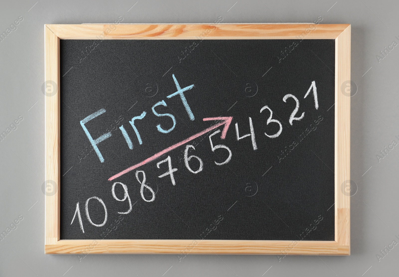 Photo of Chalkboard with word FIRST and numbers on grey background, top view. Victory concept