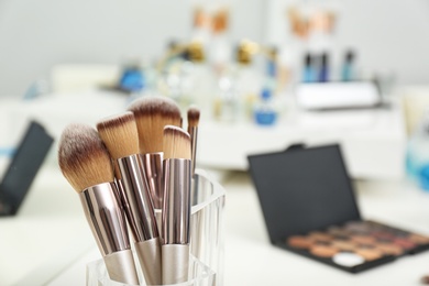 Photo of Set of brushes and other makeup products on white dressing table