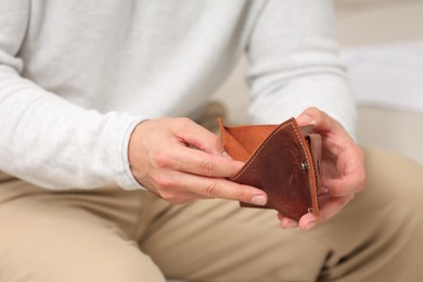 Photo of Man with empty wallet indoors, closeup. Debt problem