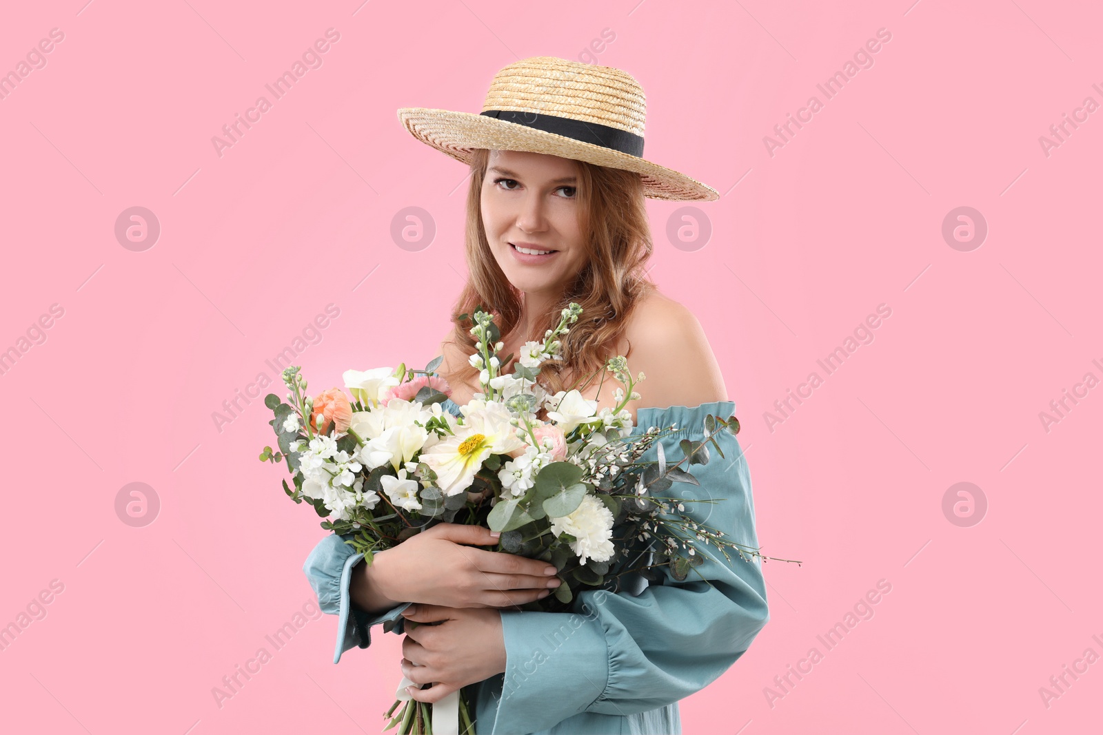 Photo of Beautiful woman in straw hat with bouquet of flowers on pink background