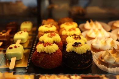 Photo of Different tasty desserts on counter in bakery shop, closeup