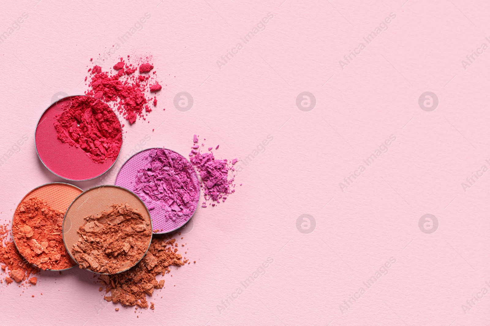 Photo of Different crushed eye shadows on pink background, flat lay. Space for text