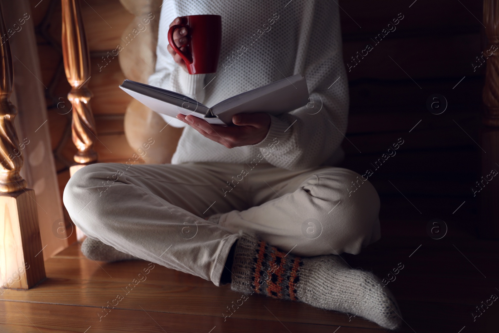 Photo of Woman with cup of coffee reading book at home, closeup