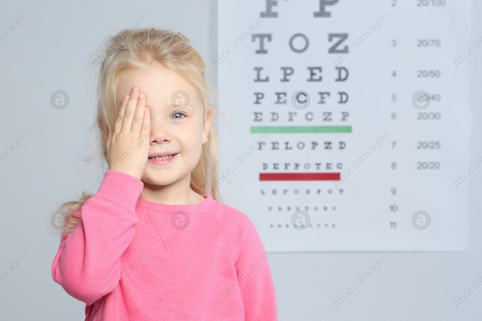 Photo of Cute little girl visiting children's doctor, space for text. Eye examination