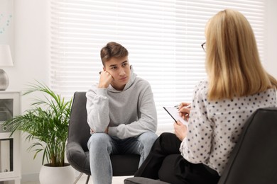 Psychologist working with teenage boy in office