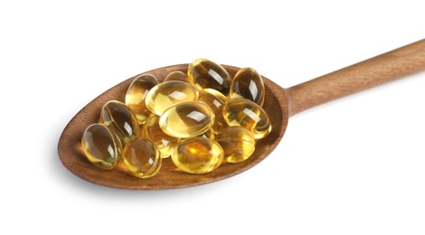 Spoon with cod liver oil pills on white background