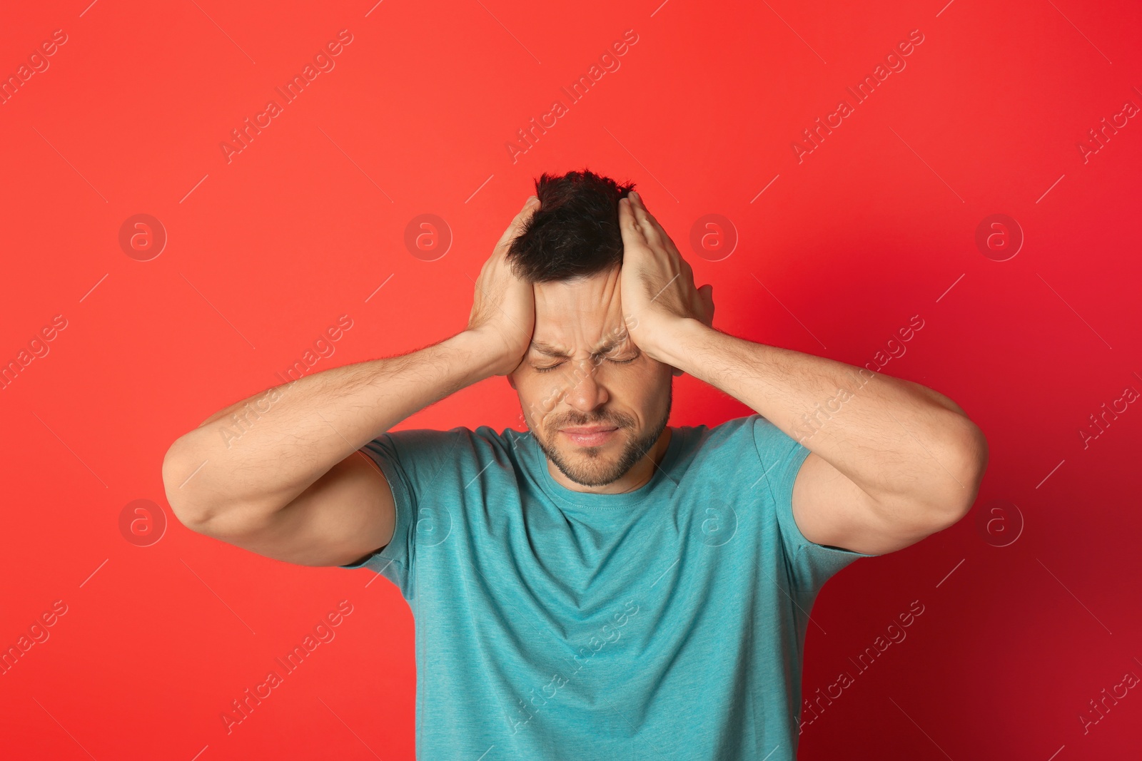 Photo of Man suffering from terrible migraine on red background