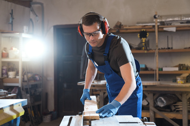 Professional carpenter working with wood in shop