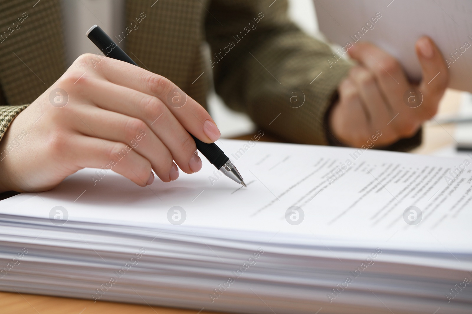 Photo of Woman signing documents at table in office, closeup