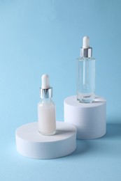 Photo of Presentation of bottles with cosmetic serums on light blue background