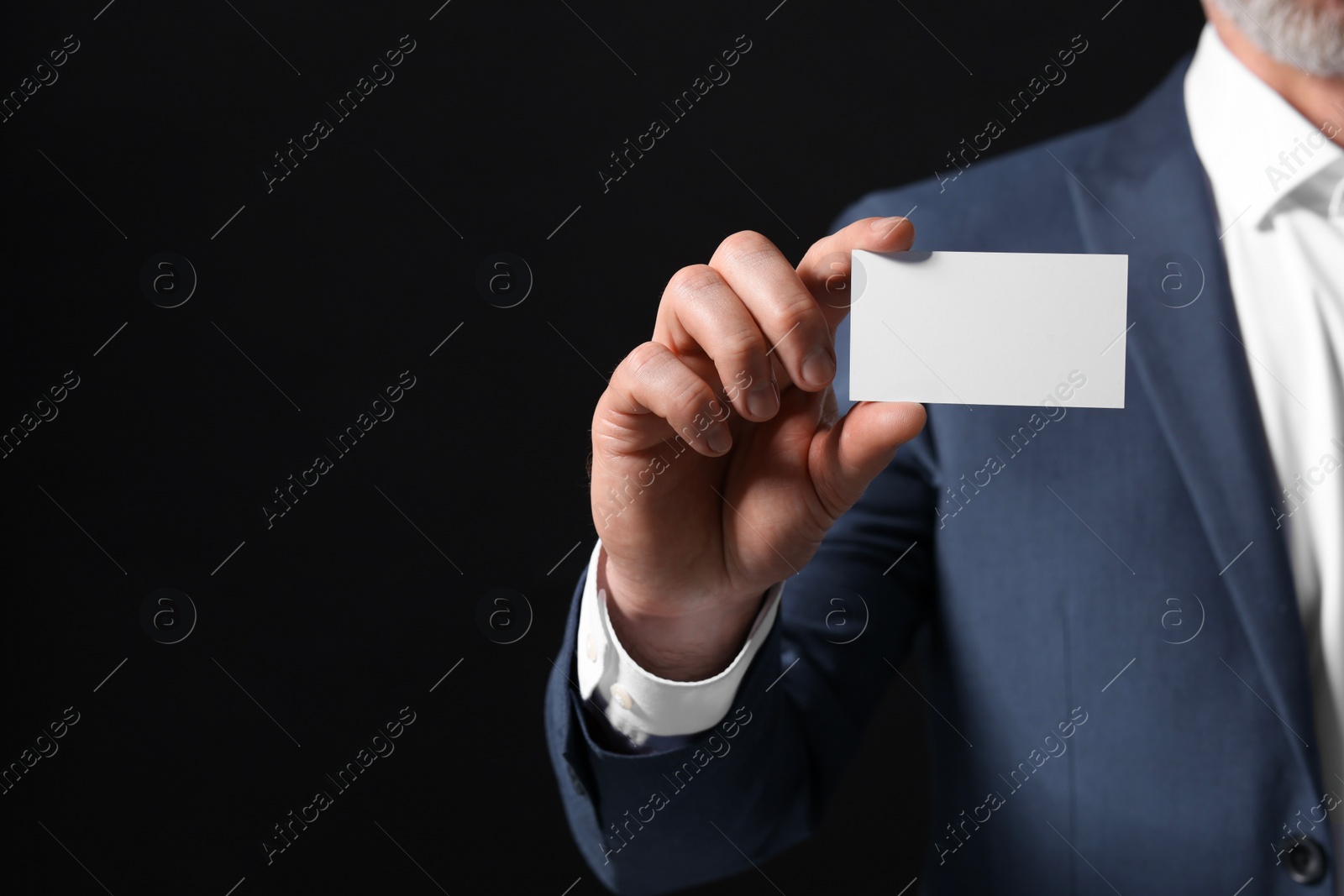 Photo of Businessman holding blank business card on black background, closeup. Space for text
