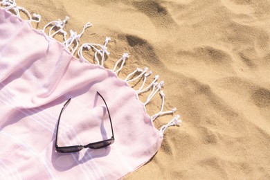 Photo of Pink blanket with stylish sunglasses on sandy beach, top view. Space for text