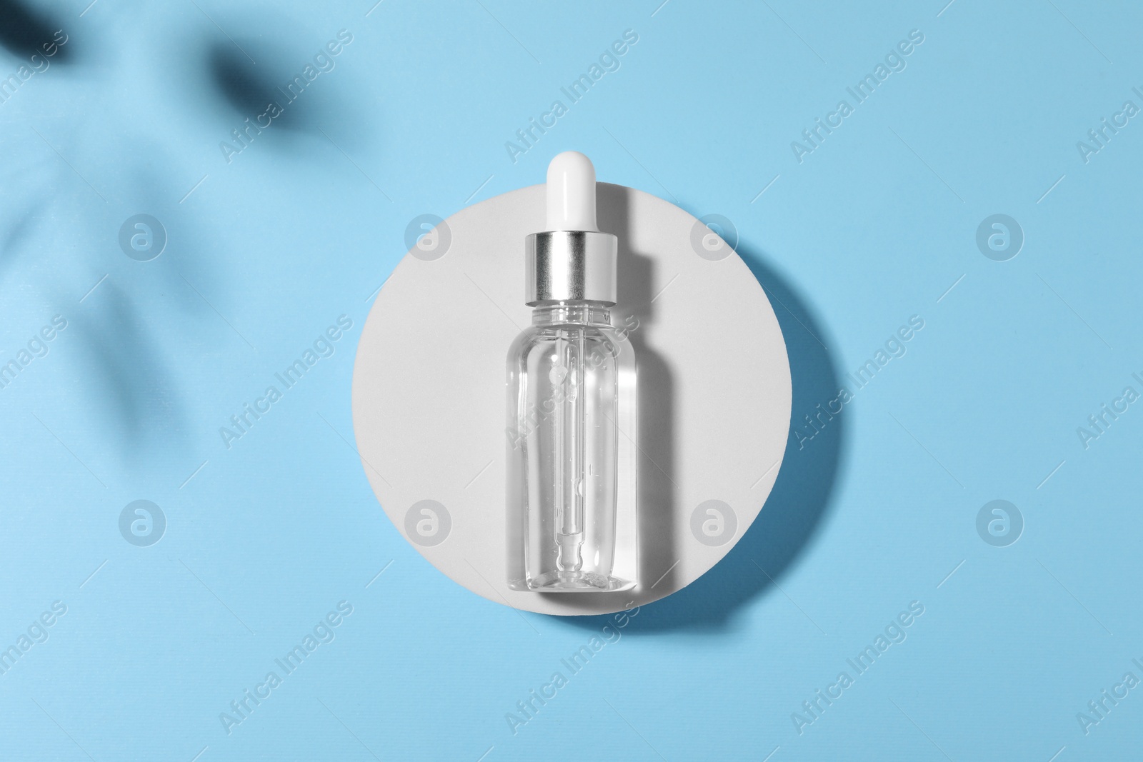 Photo of Bottle of cosmetic oil on light blue background, top view