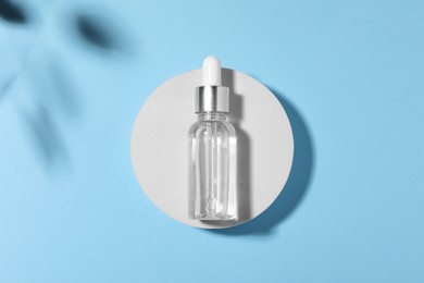Photo of Bottle of cosmetic oil on light blue background, top view